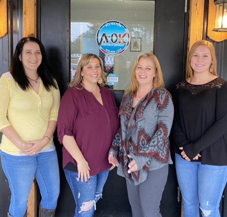 Office staff in front of a door with logo on it